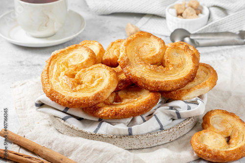 Puff. Flaky sugar Palmiers cookies in a ceramic plate on a light background. Sweet homemade cakes	