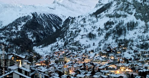 Cityscape of the Swiss village of Zermatt in Valais in winter, at dawn with snow and illuminations. The Matterhorn and the Alpine mountain range in the background.