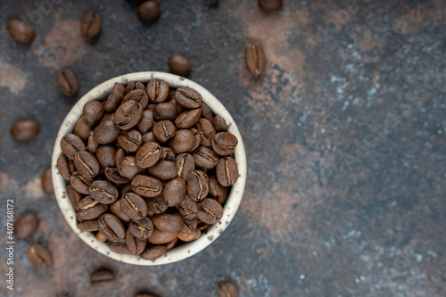Сoffee beans in a ceramic bowl - selective focus. Scattered coffee beans on a background. Flat lay with copy space. High quality photo