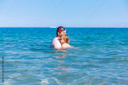 Father and little son having fun swimming and playing together in sea water at summer holidays. Family bonding, togetherness. Seaside vacation. © Anna