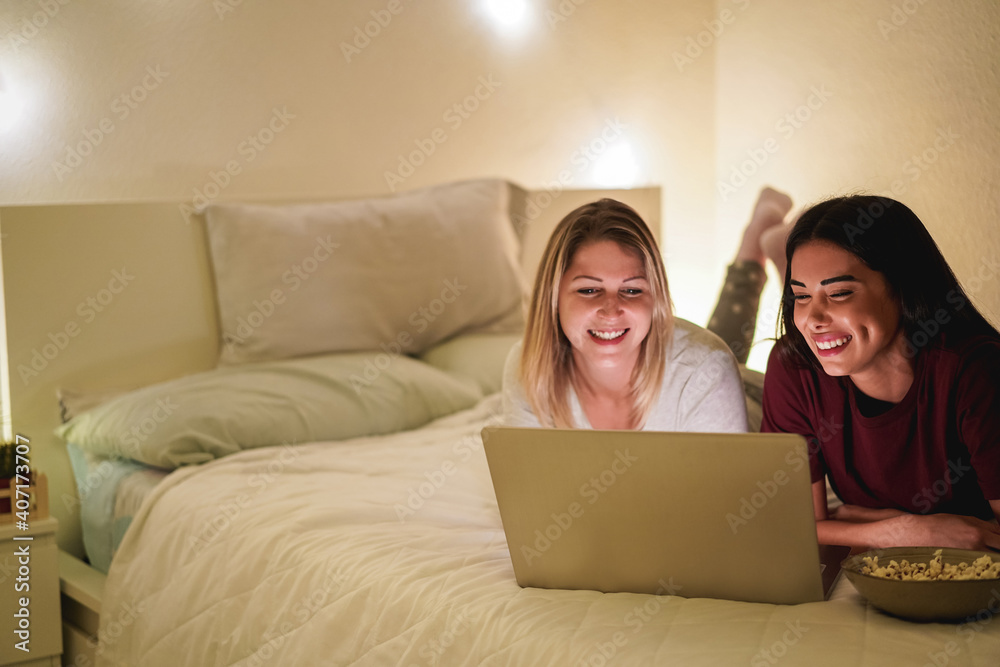 Friends watching video movie on evening in laptop computer during lockdown isolation - Focus on right girl Friends watching video movie on evening in laptop computer during lockdown isolation - Focus on right girl
