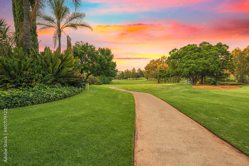 Golf cart pathway in a lush green golf course at sunset