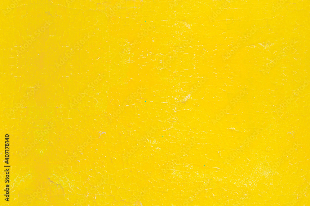 Background with a surface painted with bright yellow paint. Cracked old paint on a wooden surface