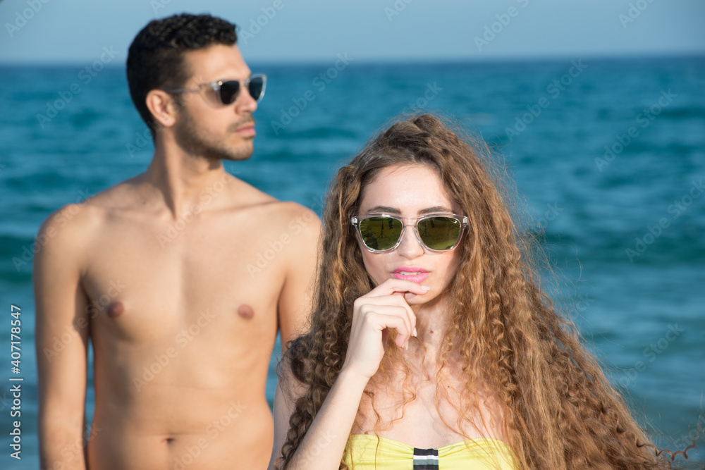 young couple wearing sunglasses enjoying the beach and stroll young couple wearing sunglasses enjoying the beach and stroll