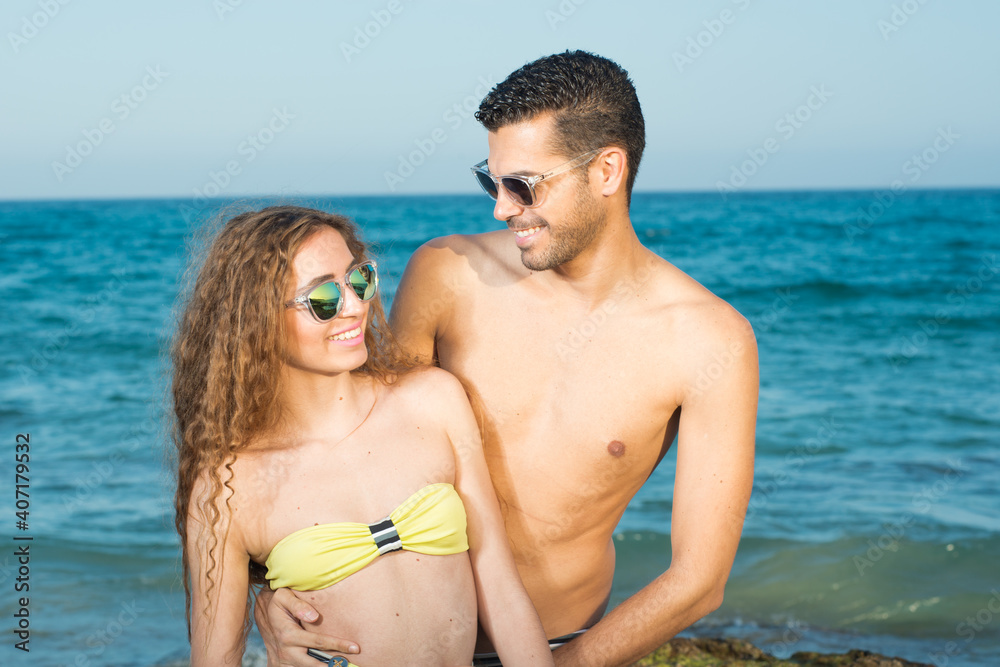 young couple wearing sunglasses enjoying the beach and stroll young couple wearing sunglasses enjoying the beach and stroll
