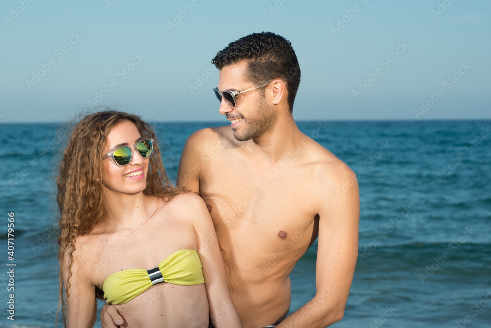 young couple wearing sunglasses enjoying the beach and stroll