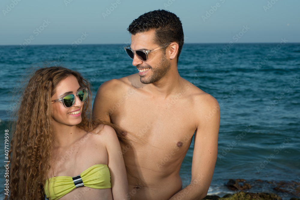 young couple wearing sunglasses enjoying the beach and stroll