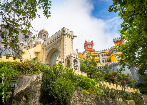 View of the clock tower, wall and palm trees in the Pena National Palace in Sintra town, Portugal