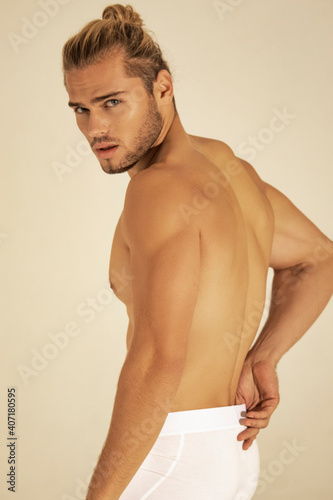 Sexy sport muscle strongface blond guy with long hair in white underwear on white isolated  font background