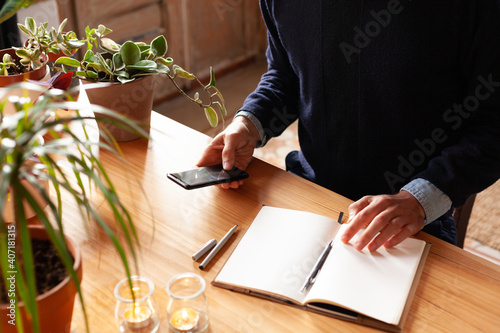 Young man working with smartphone. Modern freelancer connecting to internet via smartphone for a training. Blogger or journalist writing new article.