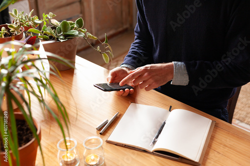 Young man pointing at smartphone screen. Modern freelancer connecting to internet via smartphone for a training. Blogger or journalist writing new article.