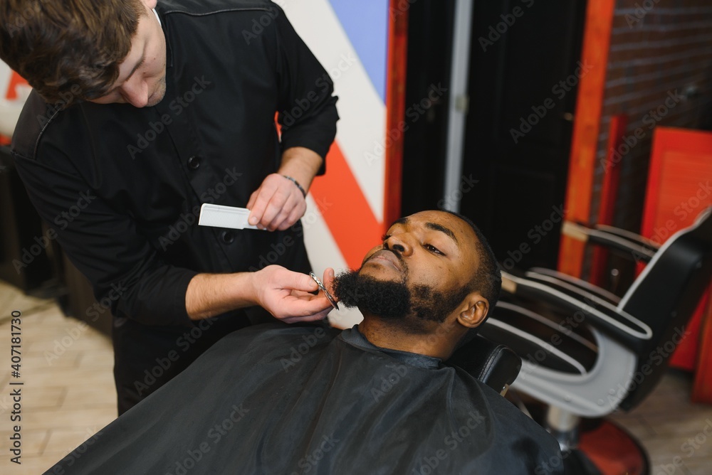 Fototapeta premium Visiting barbershop. African American man in a stylish barber shop