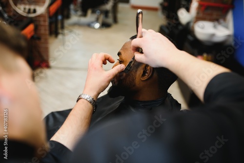 Black man in the barbershop. Cute black man makes a haircut in the African salon. Hair style. Haircut for adults.