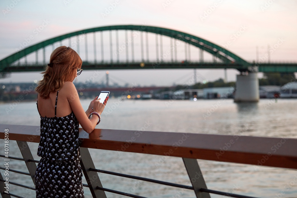 Young woman holding cellphone with blank white screen in urban city surroundings. Young woman holding cellphone with blank white screen in urban city surroundings.