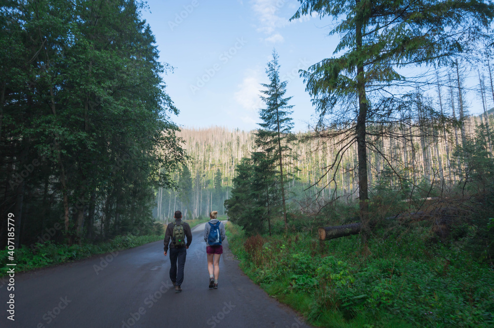 Couple Walking on the road to get ready for hiking in the mountains Couple Walking on the road to get ready for hiking in the mountains