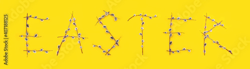 Fluffy willow branches are folded into the word Easter on a yellow background. Spring minimalistic composition, web banner. April holiday with traditional decoration and Palm Sunday concept. Top view
