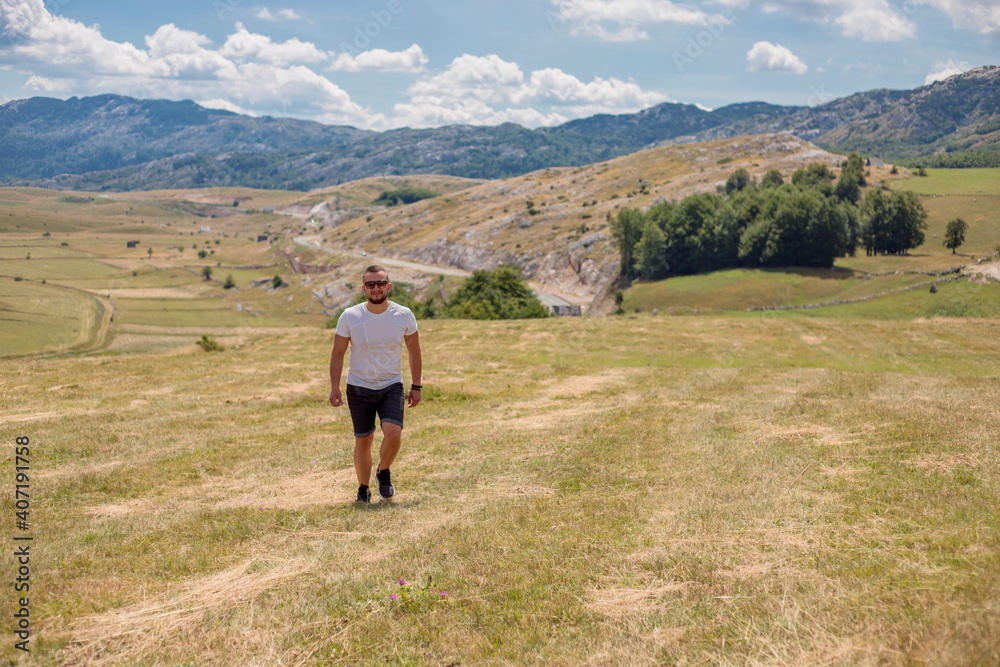 Man walking on the field on the mountain in autumn or summer day. Beautiful landscape in Montenegro. Man walking on the field on the mountain in autumn or summer day. Beautiful landscape in Montenegro.