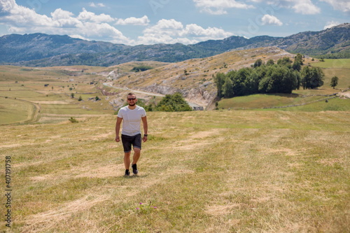  Man walking on the field on the mountain in autumn or summer day. Beautiful landscape in Montenegro. © Julija