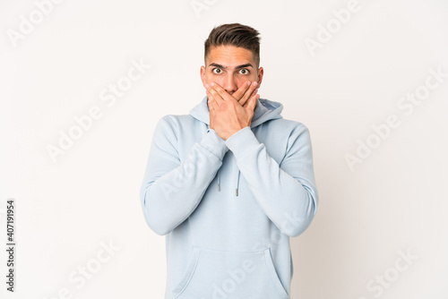 Young caucasian handsome man isolated shocked covering mouth with hands. © Asier