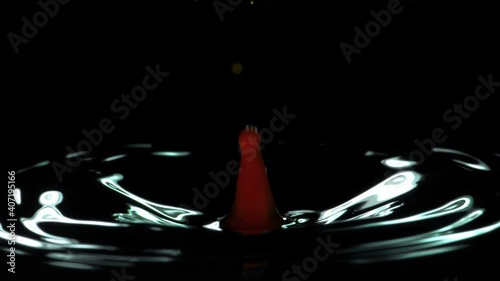 Close-up of a red water droplet falling in water in super slow motion