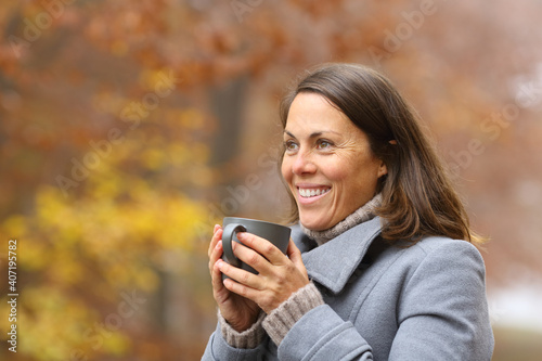 Happy woman drinking coffee in winter outside