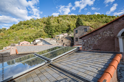Fototapeta Naklejka Na Ścianę i Meble -  Walking empty stone streets of an abandoned mountain village with a few remaining residents. View of modern solar panels on the reconstructed old roof of the house