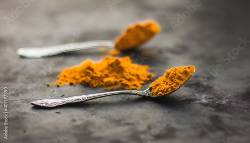 Spices turmeric in a spoon on a dark background, seasonings and healthy food