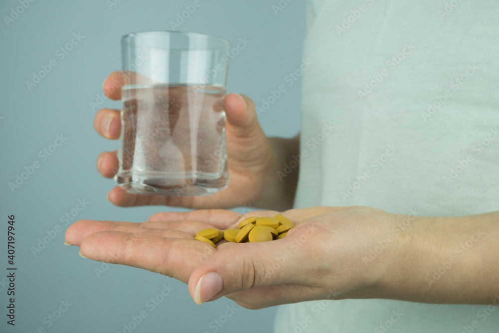 women's hands with brown coronavirus pills and a glass of water. women's hands with brown coronavirus pills and a glass of water.