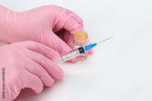A doctor in medical gloves holds a syringe and a