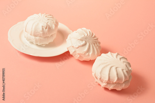 Three pieces of zefir sweet dessert served on white plate on pastel apricot background. Russian marshmallow of egg whites, fruit paste and organic apple pectin. Selective Focus, copy space

