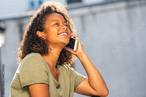 Close up side of young African American woman laughing while talking with cellphone