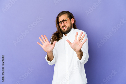 Young man with long hair look rejecting someone showing a gesture of disgust.