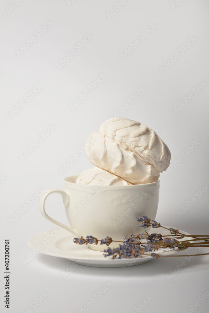 Old cup filled with souffle airy dessert zefir (zephyr) made of organic pectin and egg whites, similarly to marshmallow and meringue. Served with lavender on tea plate, isolated on white background
