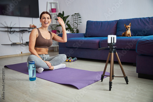 Cheerful young woman having workout online from home
