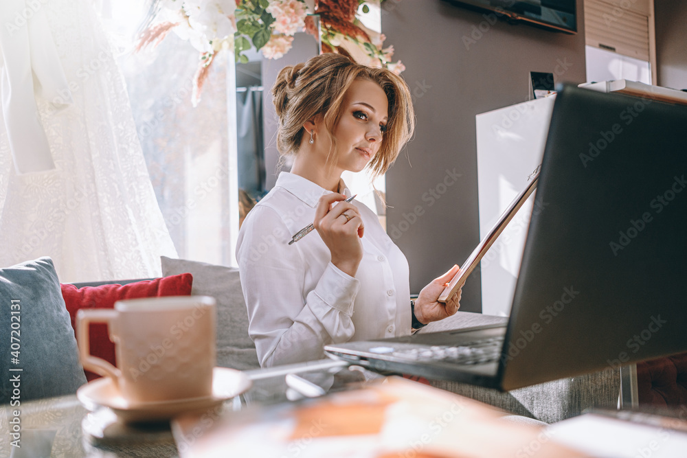young woman wedding planner in office with laptop and tablet for writing