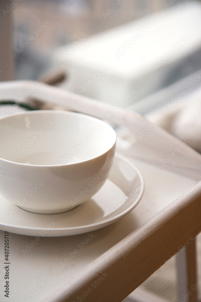 Large white ceramic cup on a saucer on a tray. Cozy home background. Still life from home interior Large white ceramic cup on a saucer on a tray. Cozy home background. Still life from home interior