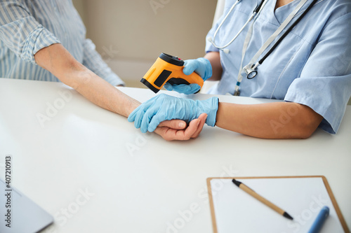 Medic using a temperature gun on an aged patient arm