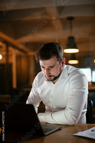 Young businessman working with laptop at office. Businessman sitting at office desk working on laptop computer.