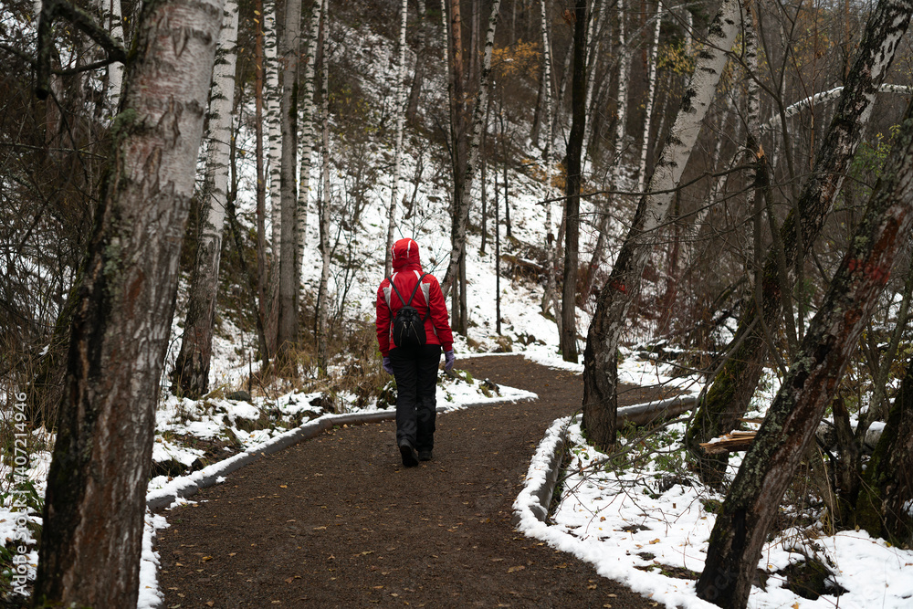 Fototapeta premium A girl in a red jacket walking along the road.