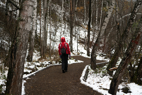 A girl in a red jacket walking along the road.