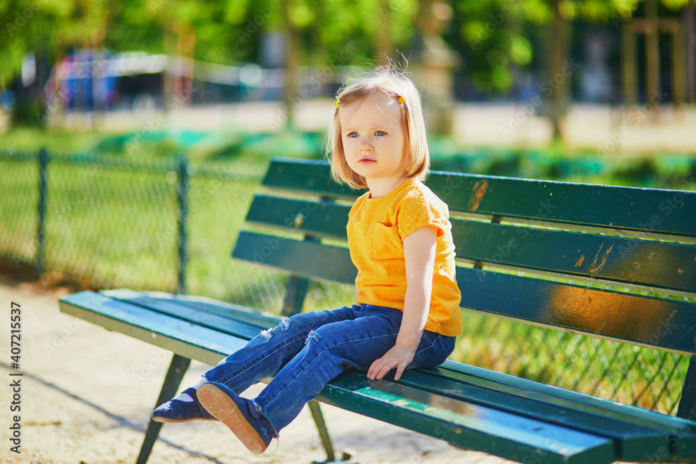 Two year old girl sitting on the bench in Paris, France Two year old girl sitting on the bench in Paris, France