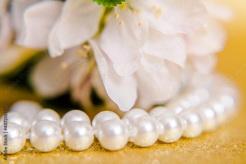 Pearl necklace and Apple blossom branch on a Golden background
Pearl necklace and Apple blossom branch on a Golden background