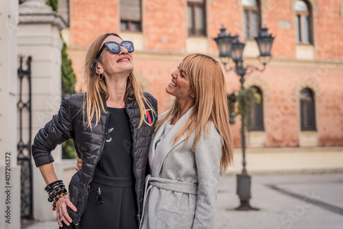 Beautiful and fashionable mature mother and young daughter outdoors in city with fresh new clothes. Fashion for mothers and daughters. Happy mother and daughter love. Family love.