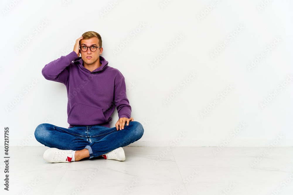 Young caucasian man sitting on the floor being shocked, she has remembered important meeting.
