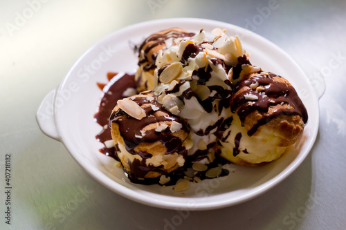 Profiteroles with ice cream, almond and chocolate on a plate. Soft focus image