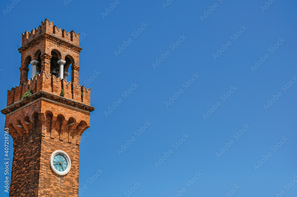 Obraz premium Detail of clock tower made of bricks with sunny blue sky in the background at Murano, a small and pleasant town near Venice. Northern Italy