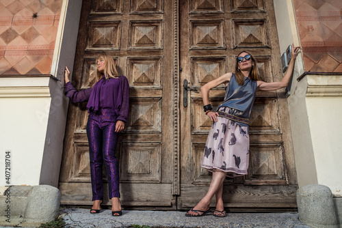 Fototapeta Naklejka Na Ścianę i Meble -  Beautiful and fashionable mature mother and young daughter outdoors in city with fresh new clothes. Fashion for mothers and daughters. Happy mother and daughter love. Family love.