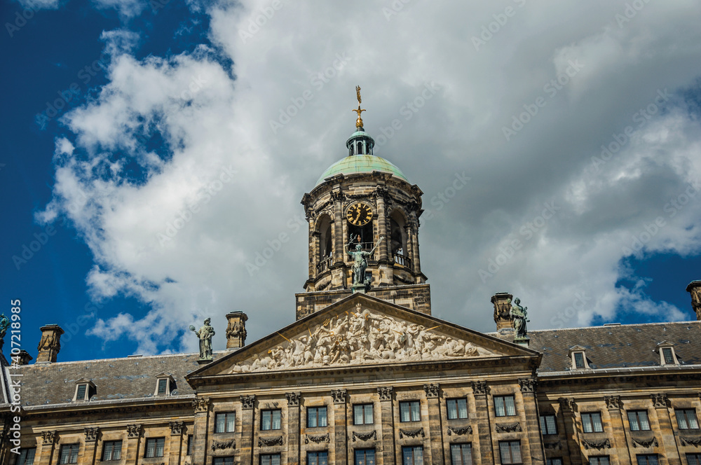 Close-up of facade with sculptures and dome with golden clock in the Royal Palace of Amsterdam. The capital of Netherlands.