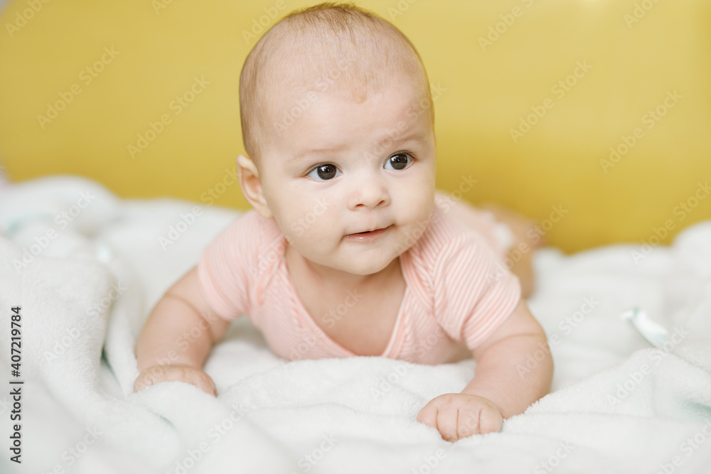 Adorable baby in sunny bedroom. Newborn baby is resting in bed with a warm soft blanket. Family morning at home. Smiling child looking at camera. Adorable baby in sunny bedroom. Newborn baby is resting in bed with a warm soft blanket. Family morning at home. Smiling child looking at camera.