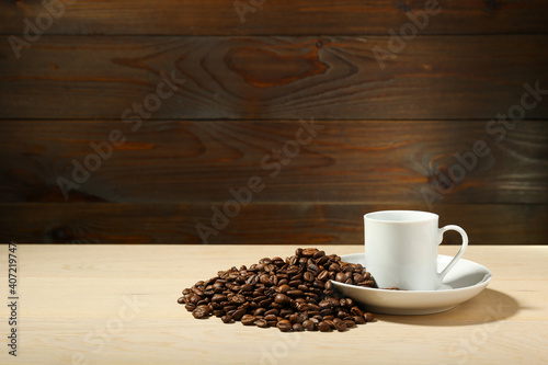 white cup of coffee and coffee beans are on a wooden background. cup of aromatic coffee is on a wooden table with copy space